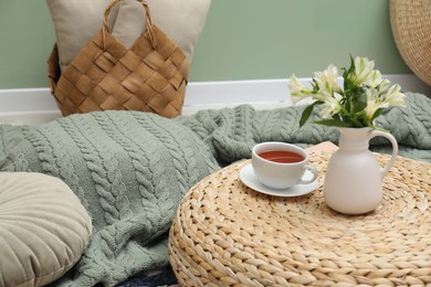 Photo of Woolen blanket, pillows, tea and flowers indoors