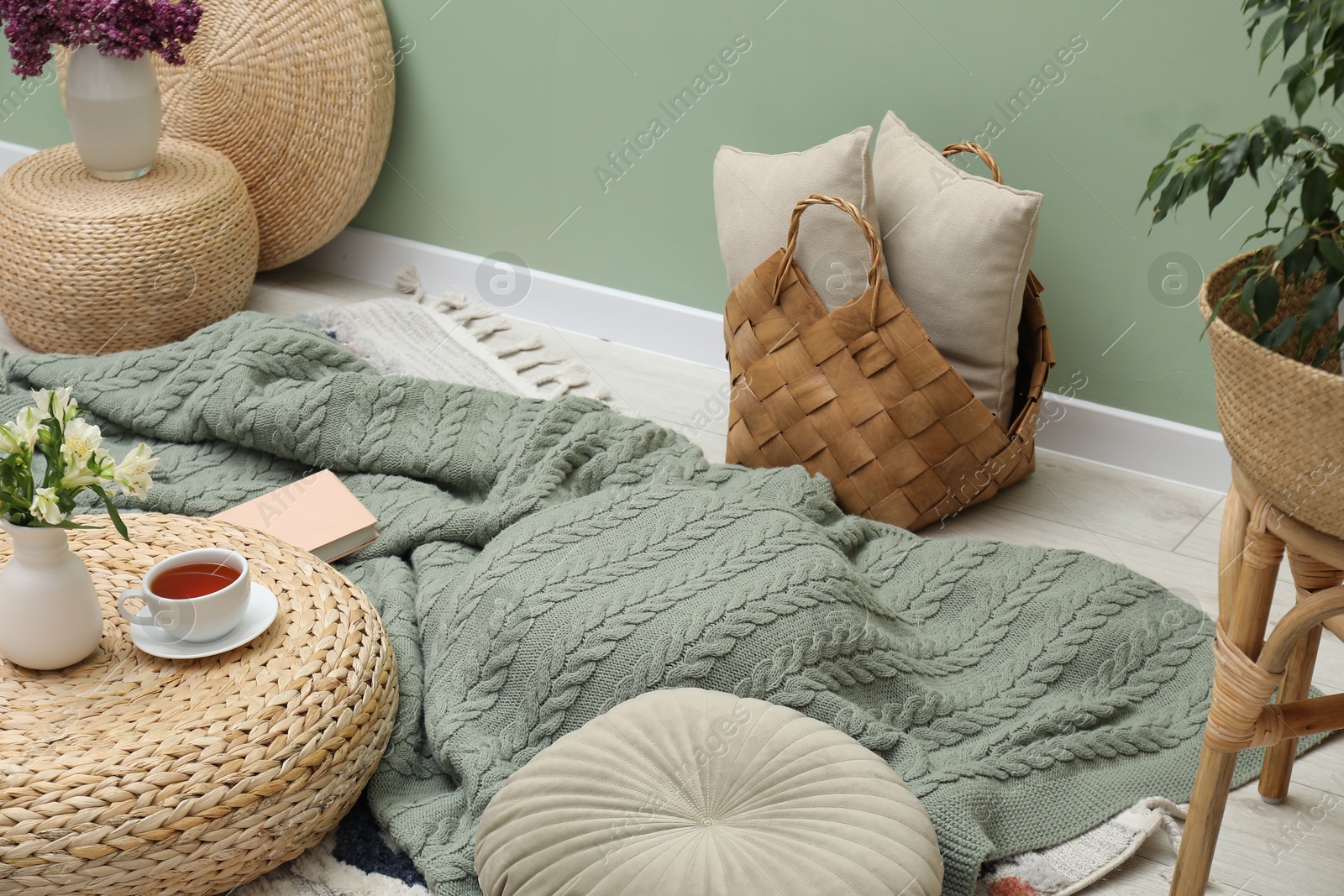 Woolen blanket, pillows, tea and flowers indoors Photo of Woolen blanket, pillows, tea and flowers indoors