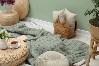 Photo of Woolen blanket, pillows, tea and flowers indoors