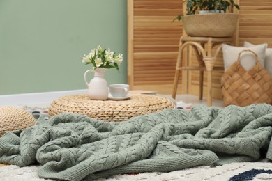 Photo of Woolen blanket, pillows, tea and flowers indoors