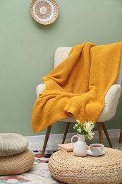 Photo of Comfortable armchair with woolen blanket, pillows and decor indoors