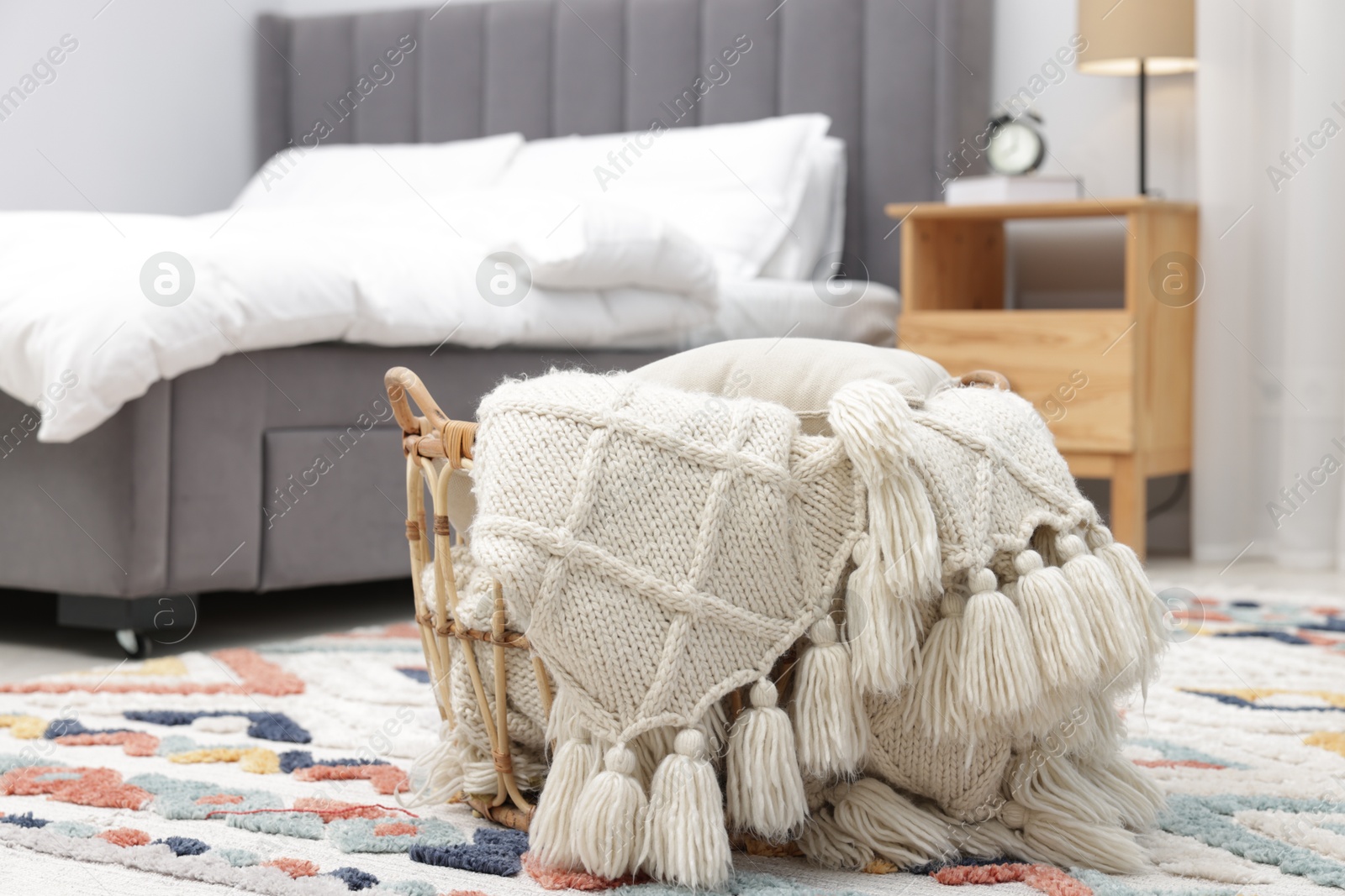 Woolen blanket in basket on floor indoors Photo of Woolen blanket in basket on floor indoors