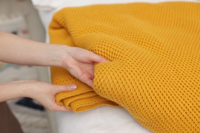 Photo of Woman folding woolen blanket at home, closeup