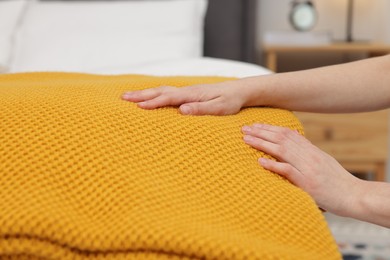 Photo of Woman folding woolen blanket at home, closeup