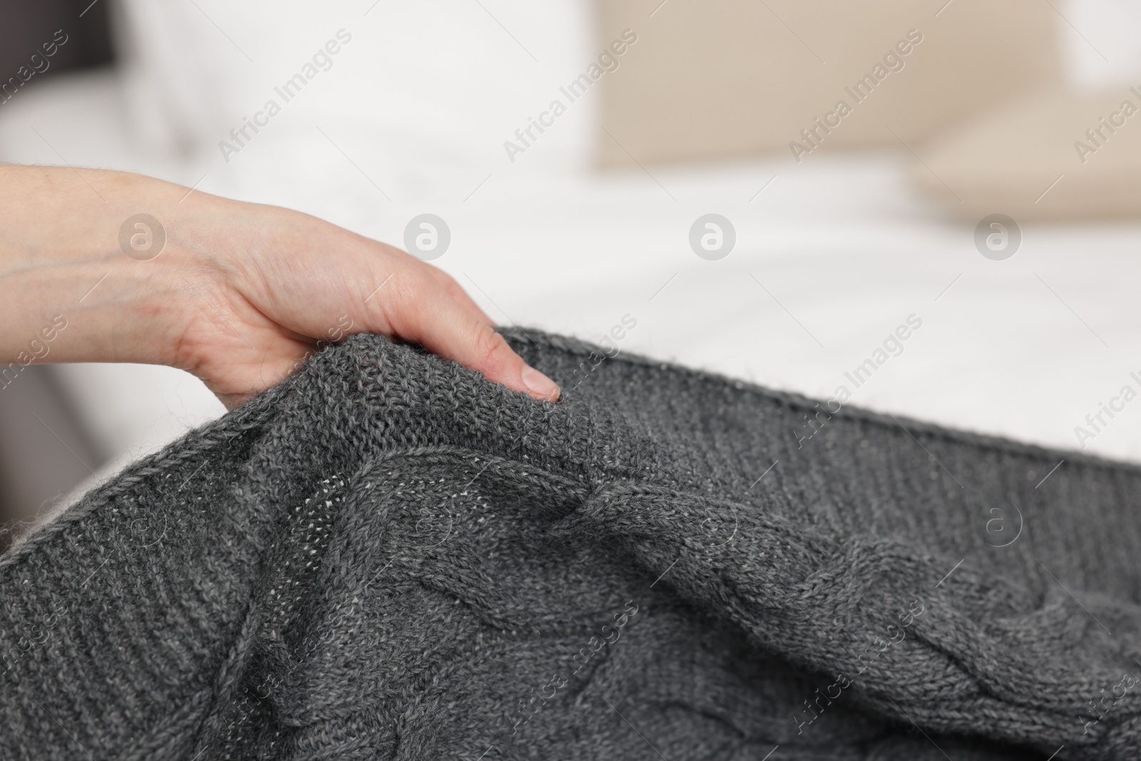 Woman putting woolen blanket on bed indoors, closeup Photo of Woman putting woolen blanket on bed indoors, closeup