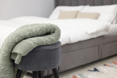 Photo of Woolen blanket on pouf indoors, space for text