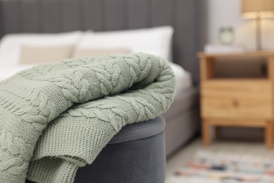 Photo of Woolen blanket on pouf indoors, closeup. Space for text