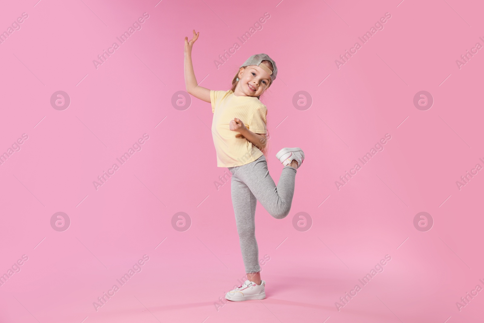 Cute little girl dancing on pink background Photo of Cute little girl dancing on pink background