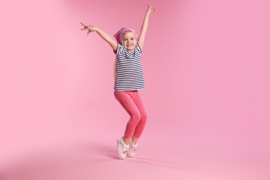 Photo of Cute little girl dancing on pink background