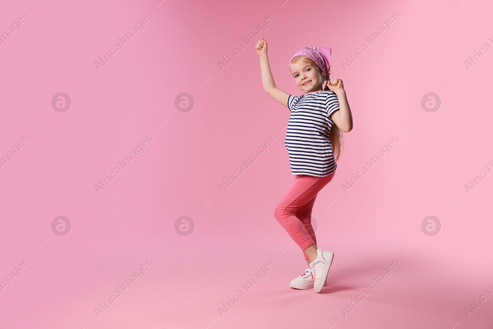 Cute little girl dancing on pink background, space for text Photo of Cute little girl dancing on pink background, space for text