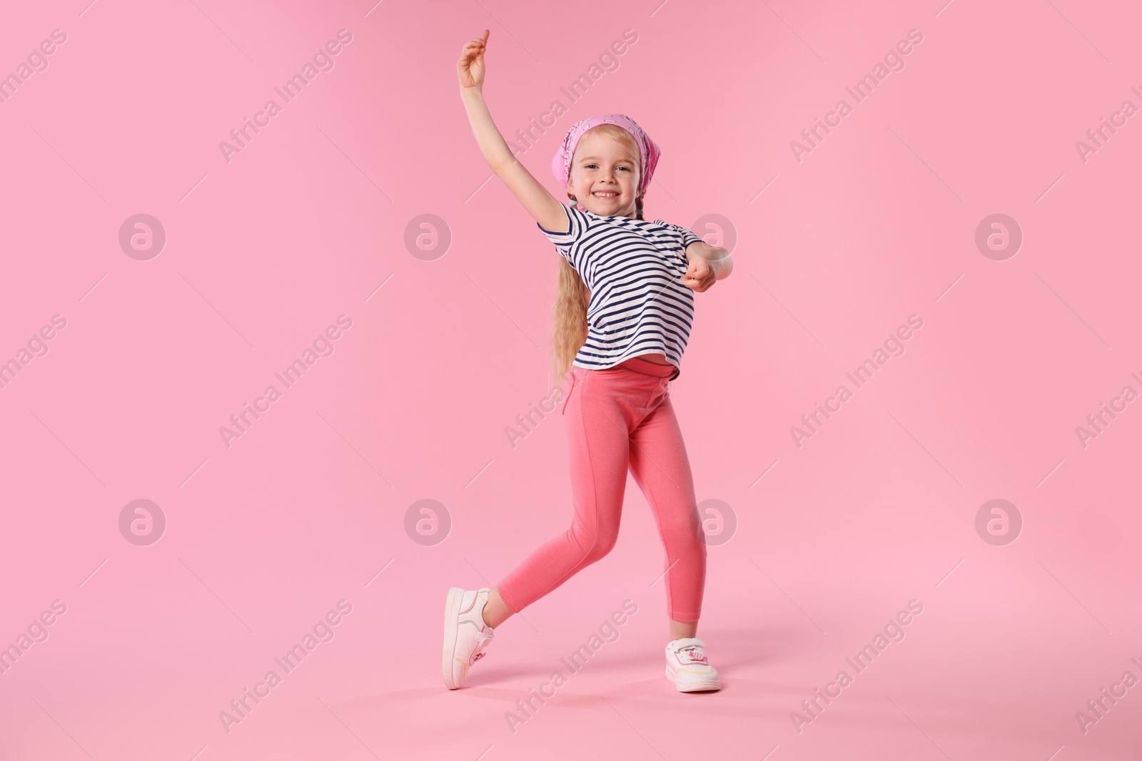 Cute little girl dancing on pink background Photo of Cute little girl dancing on pink background
