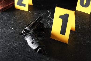 Photo of Forensic expert. Yellow evidence markers, gun and wallet on black table, closeup