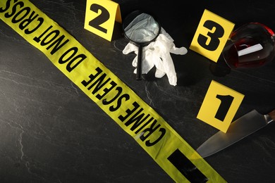 Photo of Forensic expert. Yellow crime scene tape, markers and evidences on black table, above view. Space for text