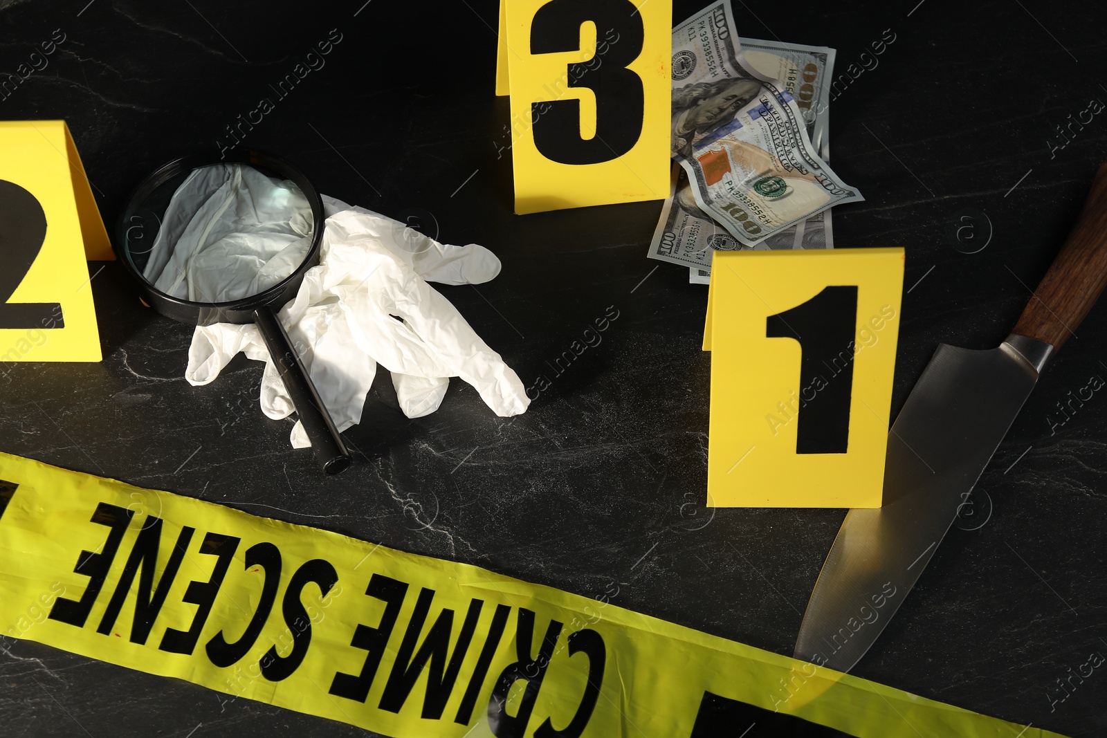 Forensic expert. Yellow crime scene tape, markers and evidences on black table, above view Photo of Forensic expert. Yellow crime scene tape, markers and evidences on black table, above view