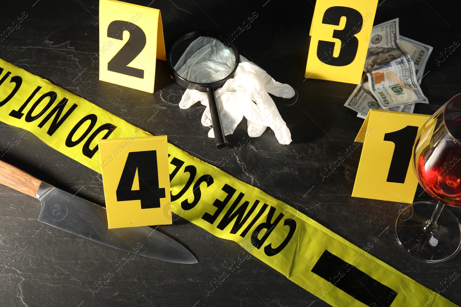 Photo of Forensic expert. Yellow crime scene tape, markers and evidences on black table, above view
