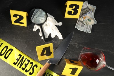 Photo of Forensic expert. Yellow crime scene tape, markers and evidences on black table, above view