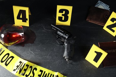Photo of Forensic expert. Yellow crime scene tape, markers and evidences on black table, above view