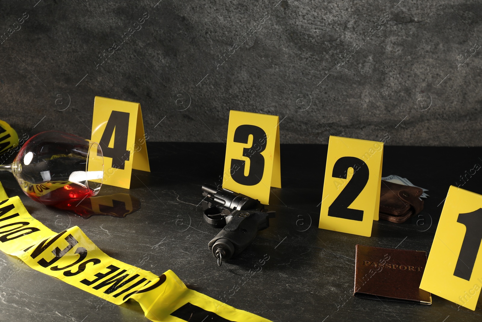 Photo of Forensic expert. Yellow crime scene tape, markers and evidences on black table, closeup