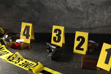 Photo of Forensic expert. Yellow crime scene tape, markers and evidences on black table, closeup