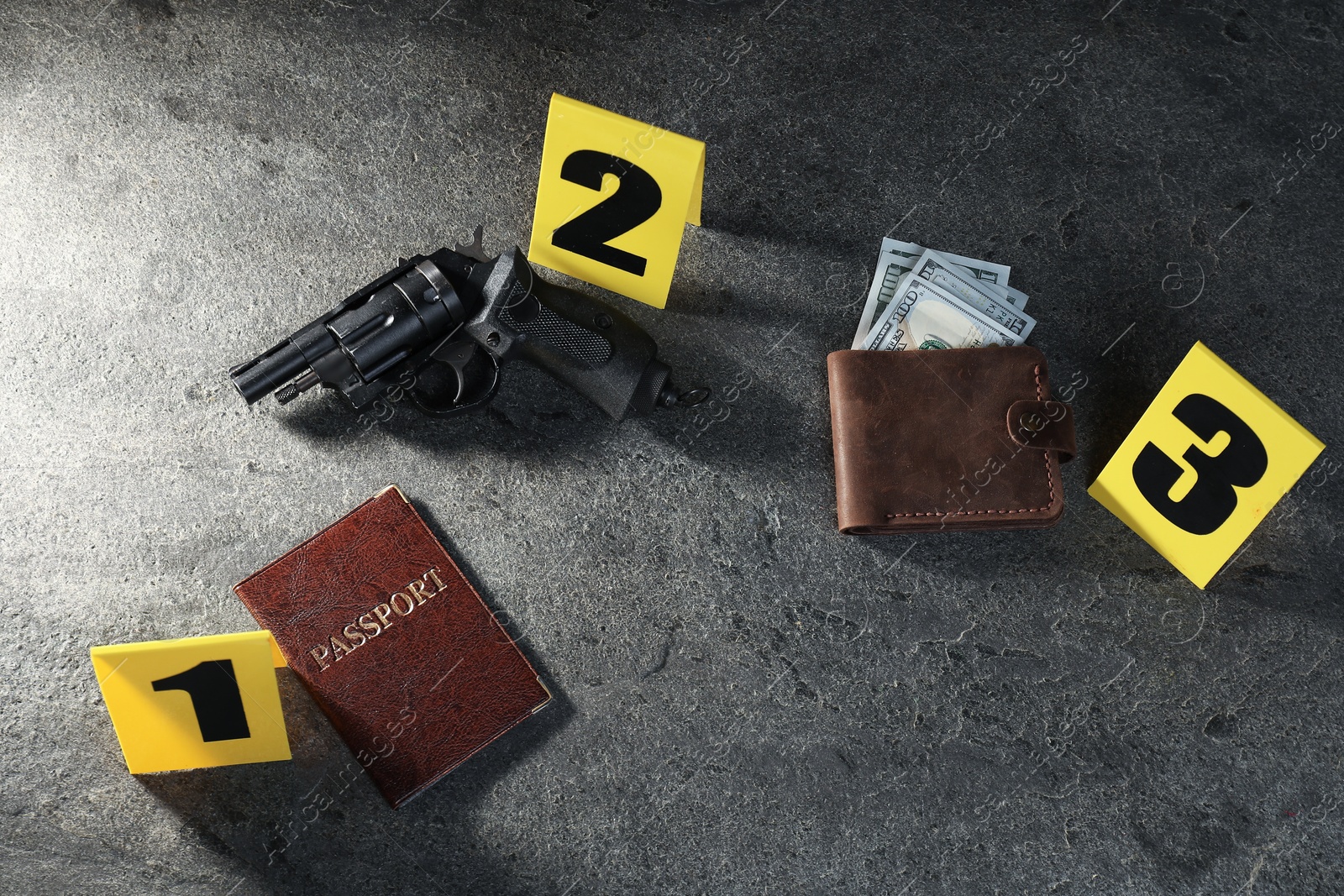 Forensic expert. Yellow evidence markers, wallet with money, gun and passport on grey table, above view Photo of Forensic expert. Yellow evidence markers, wallet with money, gun and passport on grey table, above view