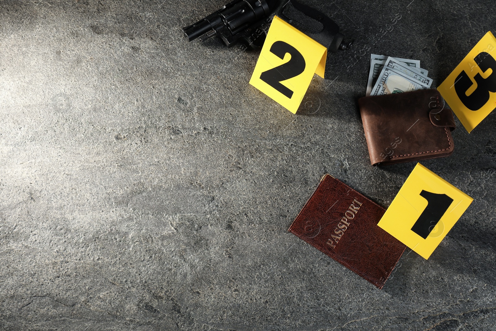 Forensic expert. Yellow evidence markers, wallet with money, gun and passport on grey table, above view. Space for text Photo of Forensic expert. Yellow evidence markers, wallet with money, gun and passport on grey table, above view. Space for text