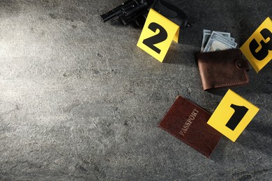 Photo of Forensic expert. Yellow evidence markers, wallet with money, gun and passport on grey table, above view. Space for text