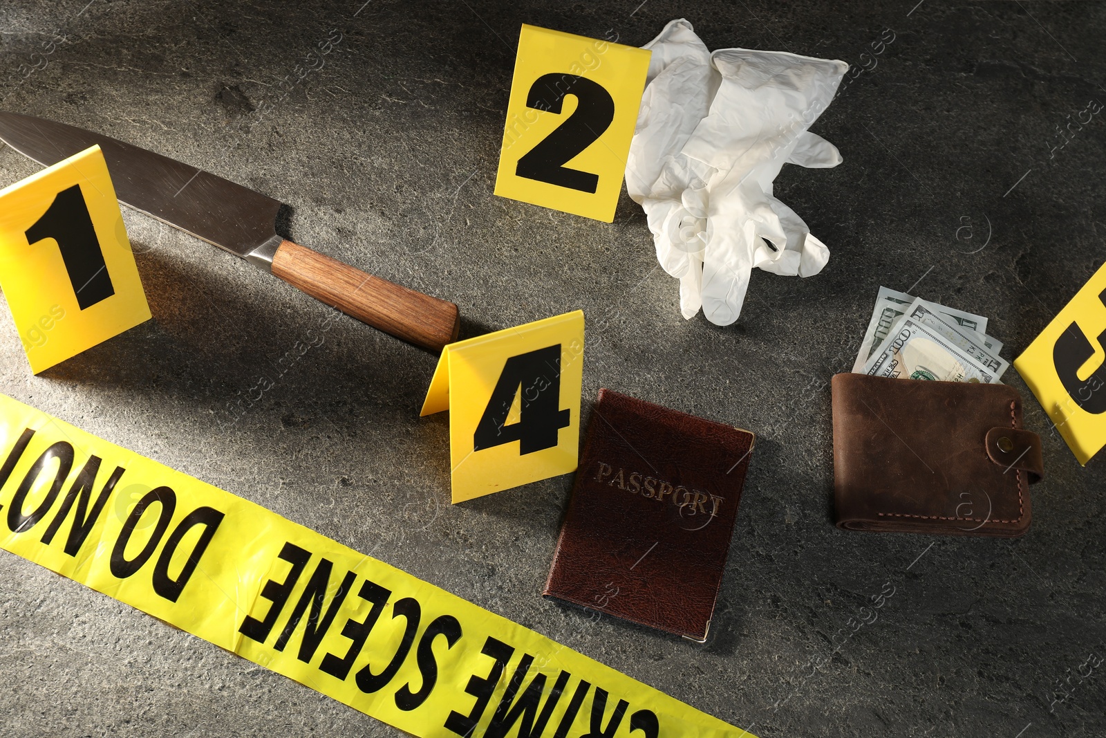 Forensic expert. Yellow crime scene tape, markers and evidences on grey table, above view Photo of Forensic expert. Yellow crime scene tape, markers and evidences on grey table, above view