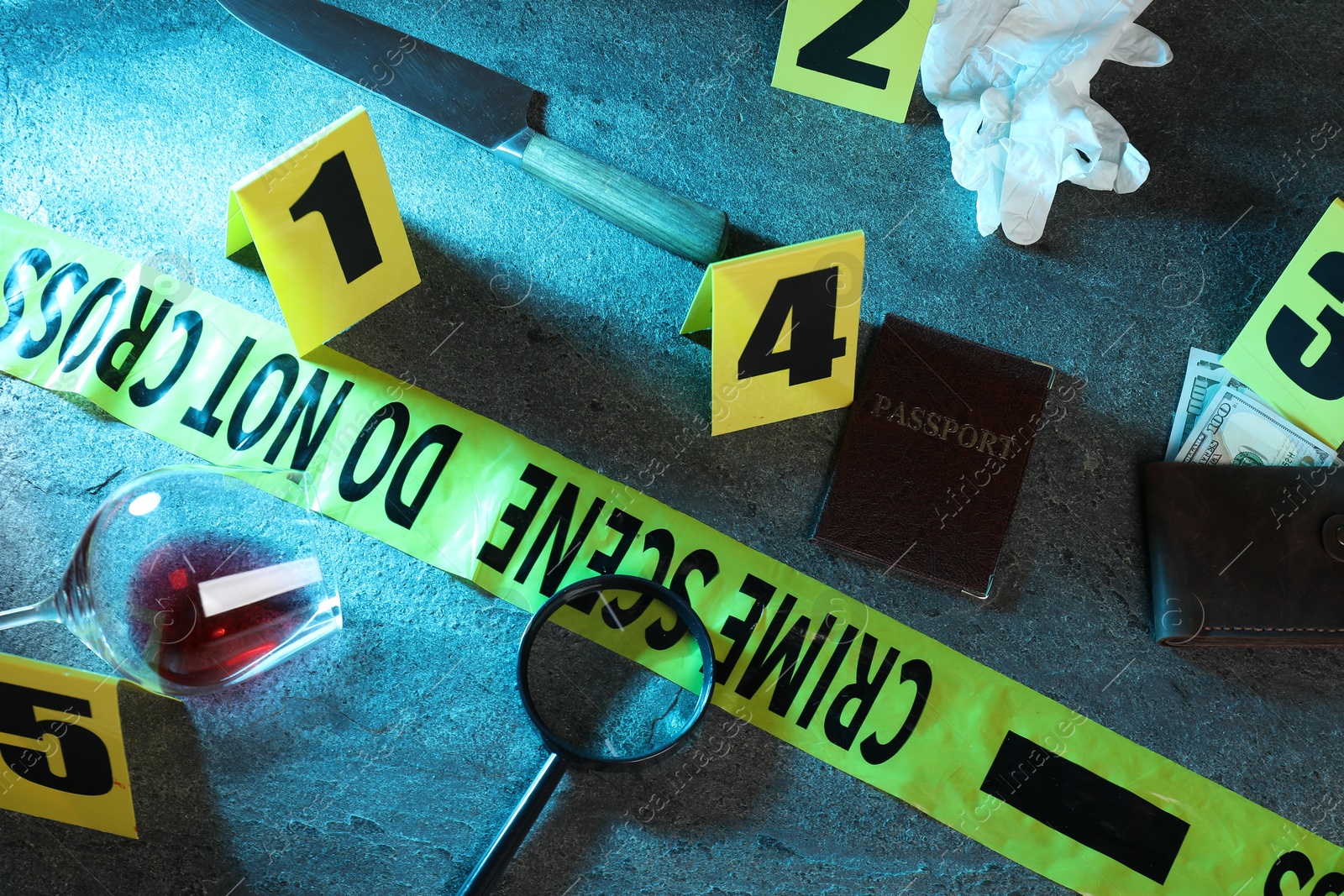 Forensic expert. Yellow crime scene tape, markers and evidences on grey table, above view Photo of Forensic expert. Yellow crime scene tape, markers and evidences on grey table, above view