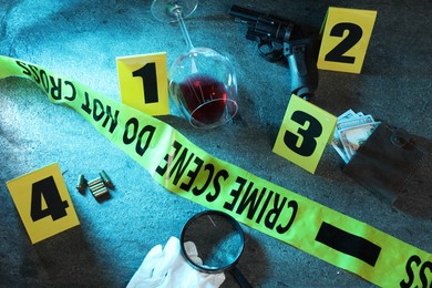 Photo of Forensic expert. Yellow crime scene tape, markers and evidences on grey table, above view