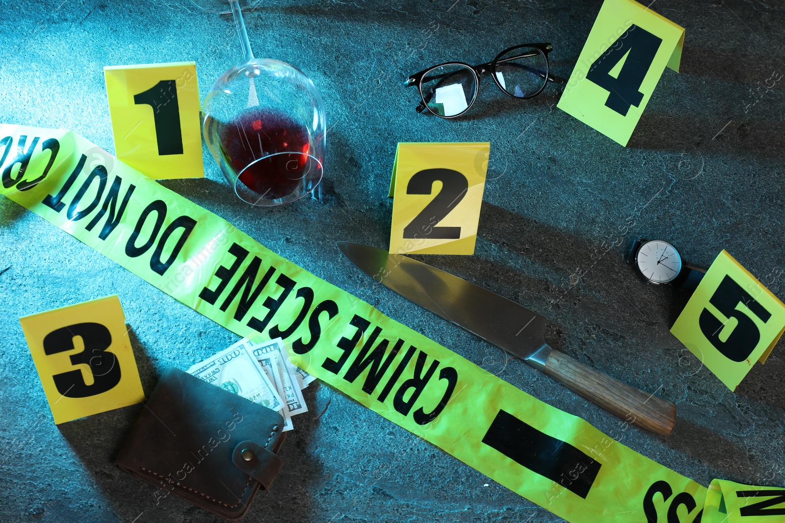 Photo of Forensic expert. Yellow crime scene tape, markers and evidences on grey table, above view