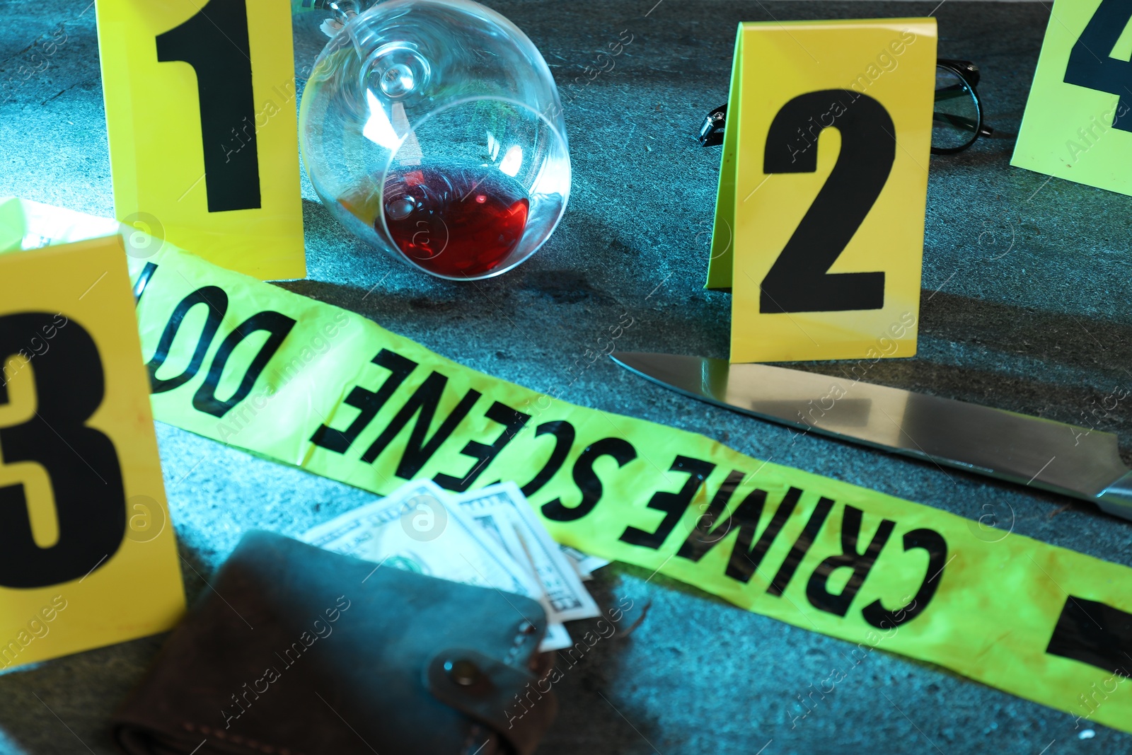 Forensic expert. Yellow crime scene tape, markers, wallet with money, knife and glass of wine on grey table, closeup Photo of Forensic expert. Yellow crime scene tape, markers, wallet with money, knife and glass of wine on grey table, closeup