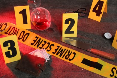 Photo of Forensic expert. Yellow crime scene tape, markers and evidences on grey table, closeup