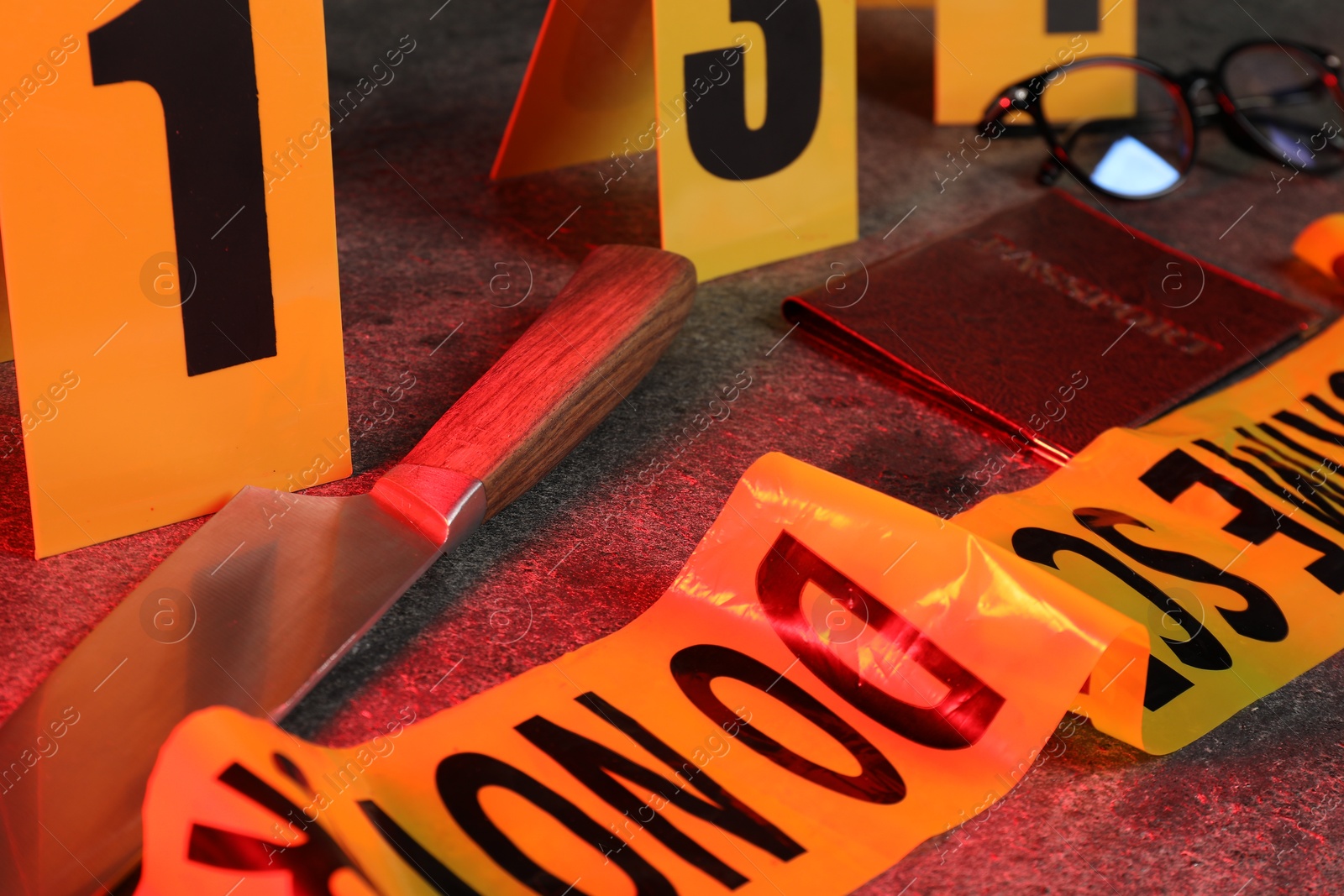 Forensic expert. Yellow crime scene tape, markers, knife, passport and glasses on grey table, closeup Photo of Forensic expert. Yellow crime scene tape, markers, knife, passport and glasses on grey table, closeup