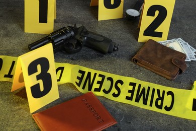Photo of Forensic expert. Yellow crime scene tape, markers and evidences on grey table, closeup