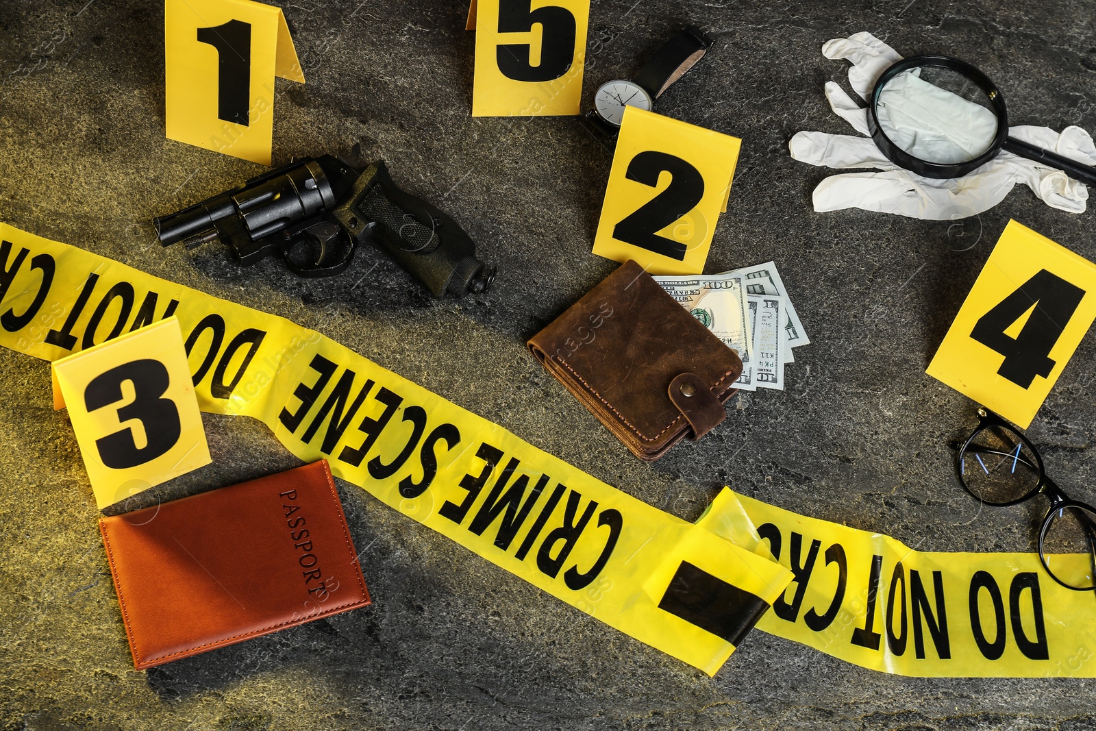 Photo of Forensic expert. Yellow crime scene tape, markers and evidences on grey table, above view
