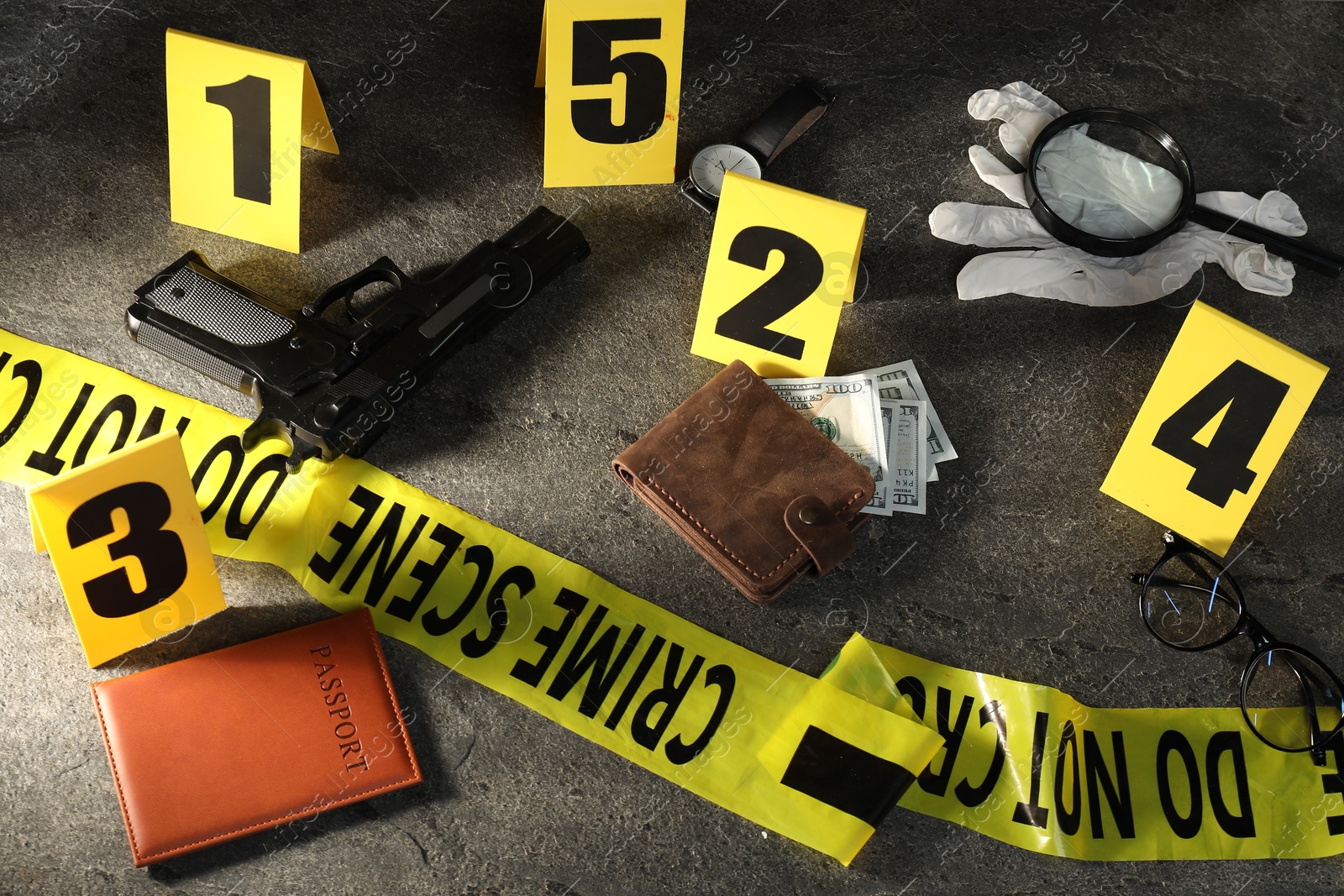 Forensic expert. Yellow crime scene tape, markers and evidences on grey table, above view Photo of Forensic expert. Yellow crime scene tape, markers and evidences on grey table, above view