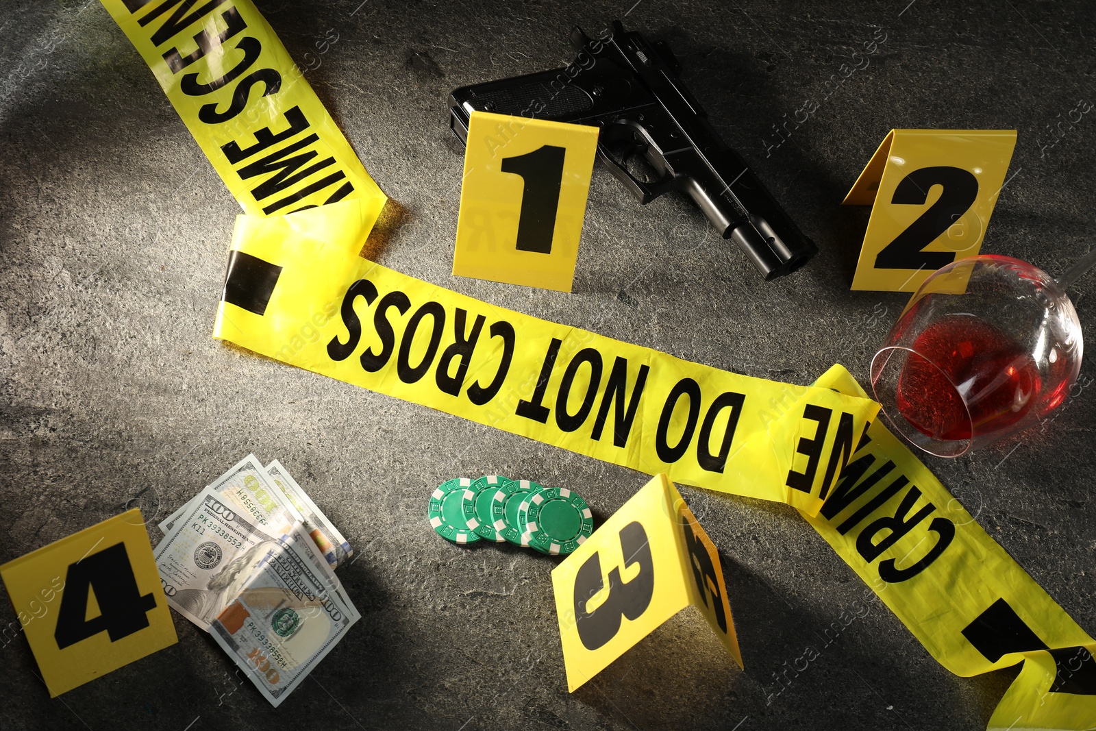 Forensic expert. Yellow crime scene tape, markers and evidences on grey table, above view Photo of Forensic expert. Yellow crime scene tape, markers and evidences on grey table, above view