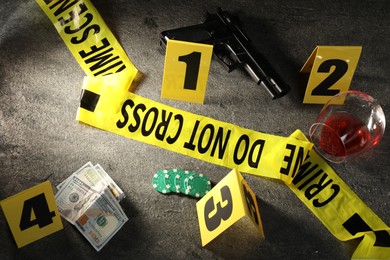 Photo of Forensic expert. Yellow crime scene tape, markers and evidences on grey table, above view