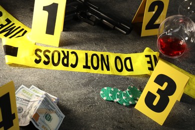Photo of Forensic expert. Yellow crime scene tape, markers and evidences on grey table, closeup