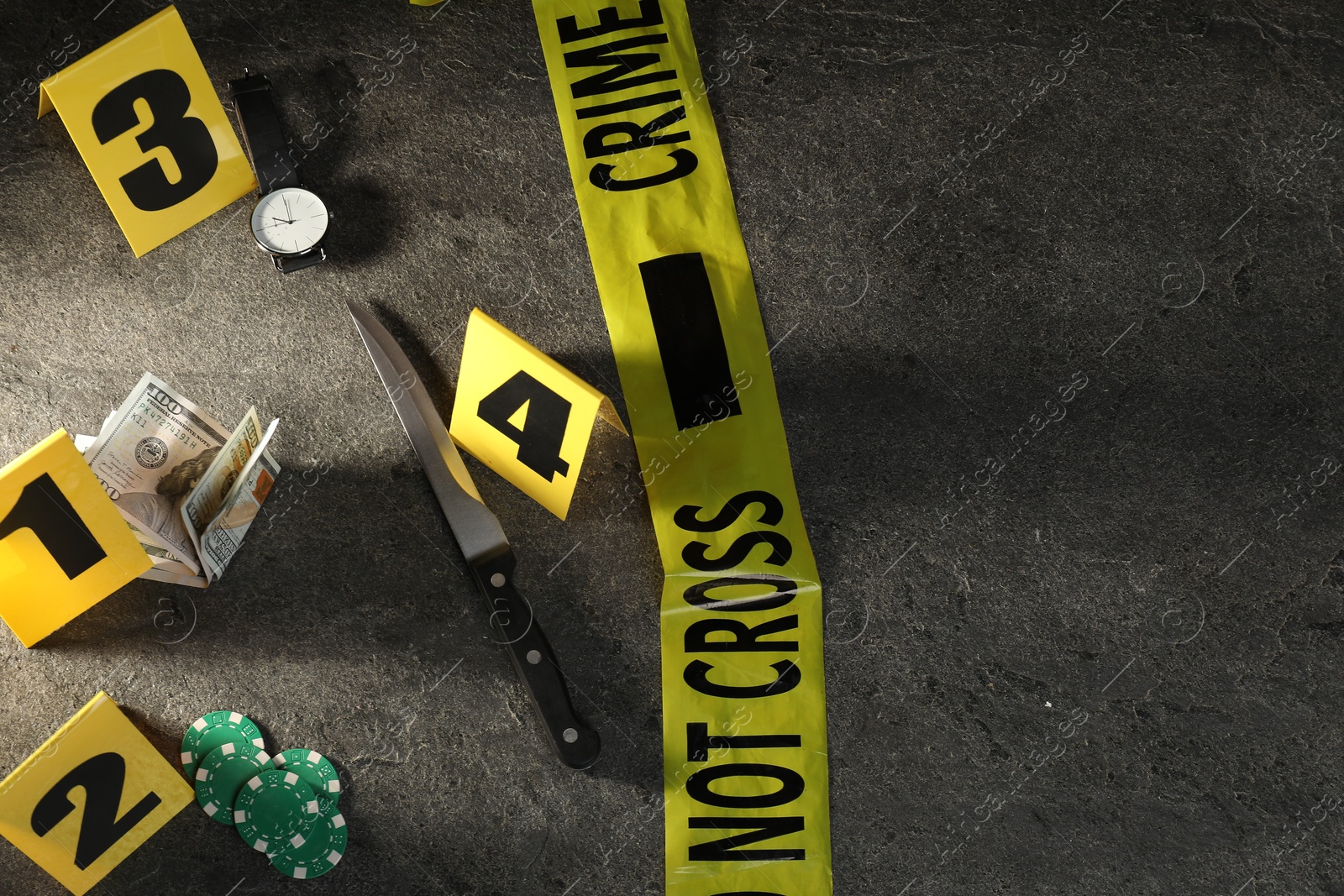 Photo of Forensic expert. Yellow crime scene tape, markers and evidences on grey table, above view. Space for text