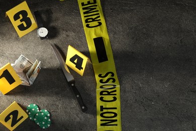 Photo of Forensic expert. Yellow crime scene tape, markers and evidences on grey table, above view. Space for text