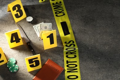 Photo of Forensic expert. Yellow crime scene tape, markers and evidences on grey table, above view. Space for text