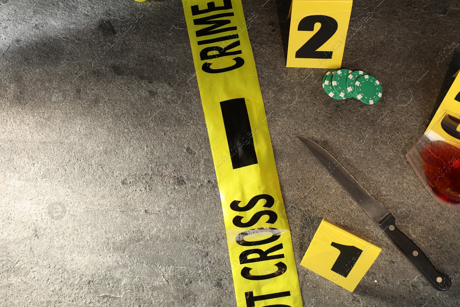 Forensic expert. Yellow crime scene tape, markers, knife and glass of wine on grey table, flat lay. Space for text Photo of Forensic expert. Yellow crime scene tape, markers, knife and glass of wine on grey table, flat lay. Space for text