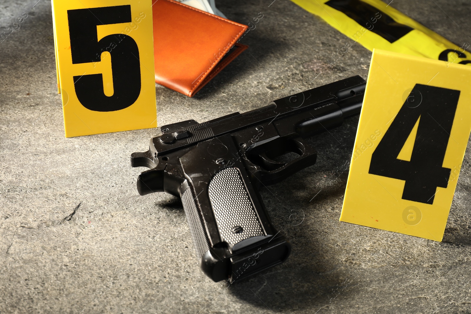 Forensic expert. Yellow crime scene tape, gun and passport on grey table, closeup Photo of Forensic expert. Yellow crime scene tape, gun and passport on grey table, closeup