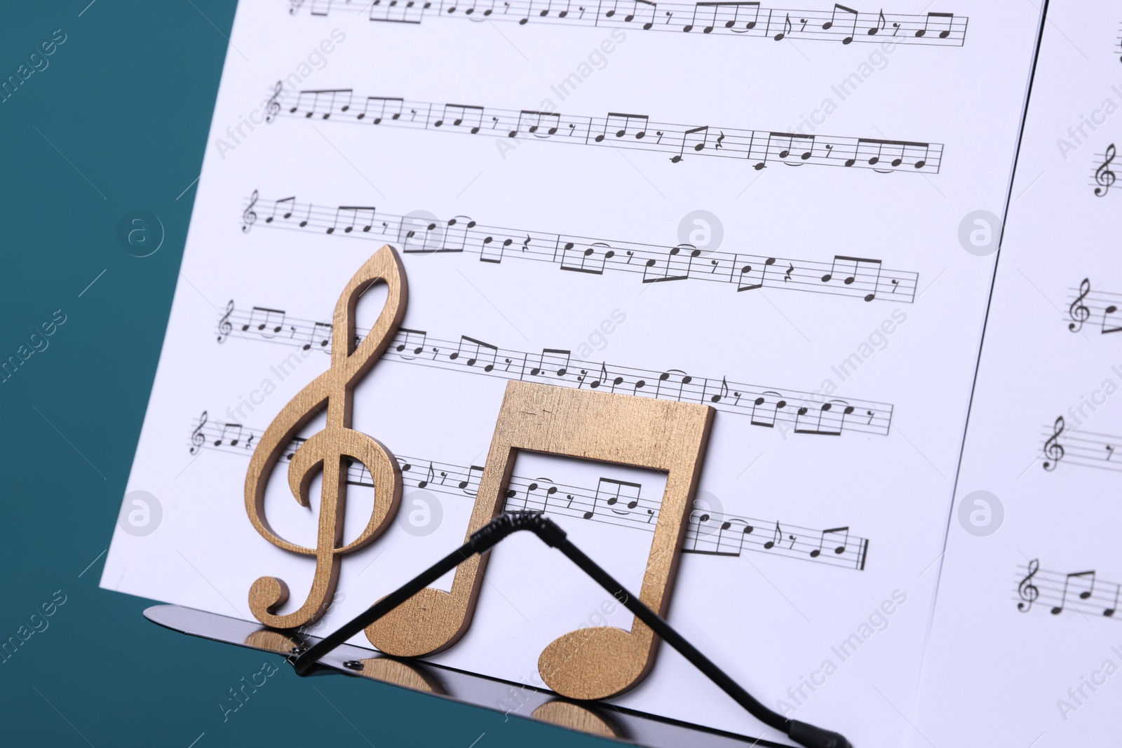 Stand with music sheets and wooden notes on light blue background, closeup Photo of Stand with music sheets and wooden notes on light blue background, closeup
