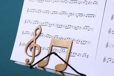 Photo of Stand with music sheets and wooden notes on light blue background, closeup