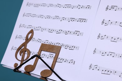 Photo of Stand with music sheets and wooden notes on light blue background, closeup