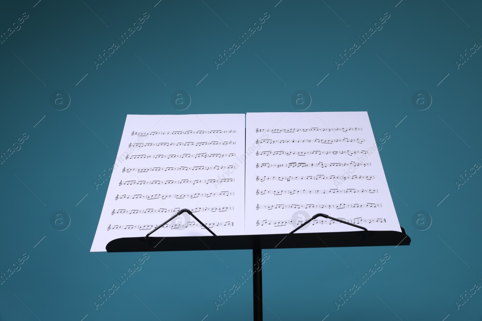 Note stand with music sheets on light blue background Photo of Note stand with music sheets on light blue background