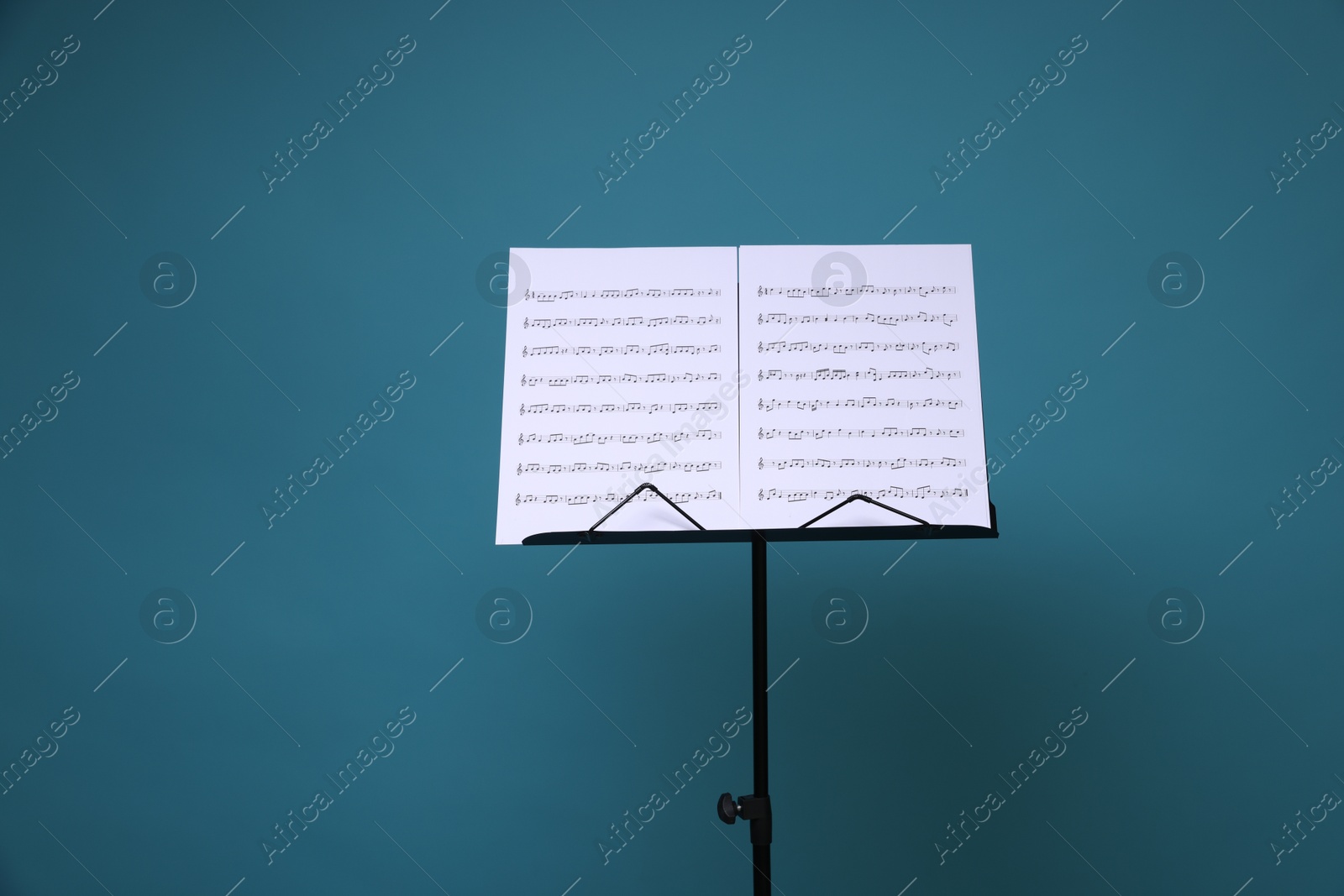 Note stand with music sheets on light blue background, space for text Photo of Note stand with music sheets on light blue background, space for text