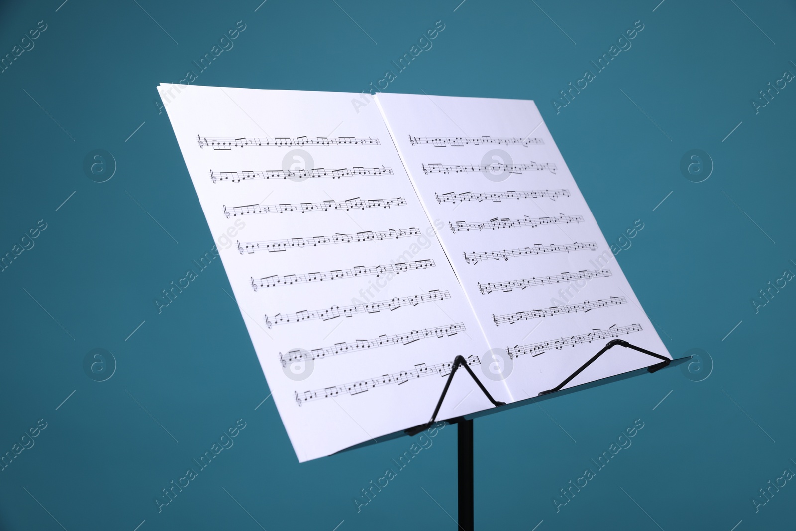 Note stand with music sheets on light blue background, closeup Photo of Note stand with music sheets on light blue background, closeup